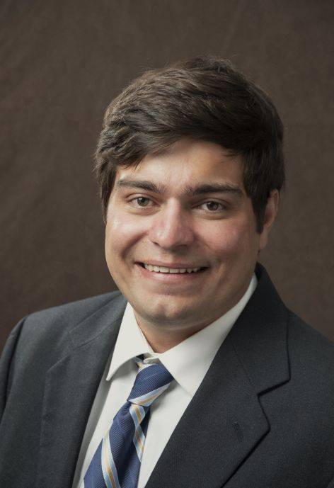 Dalton Nichols wearing a black suit jacket, white button-up, and blue patterned tie.