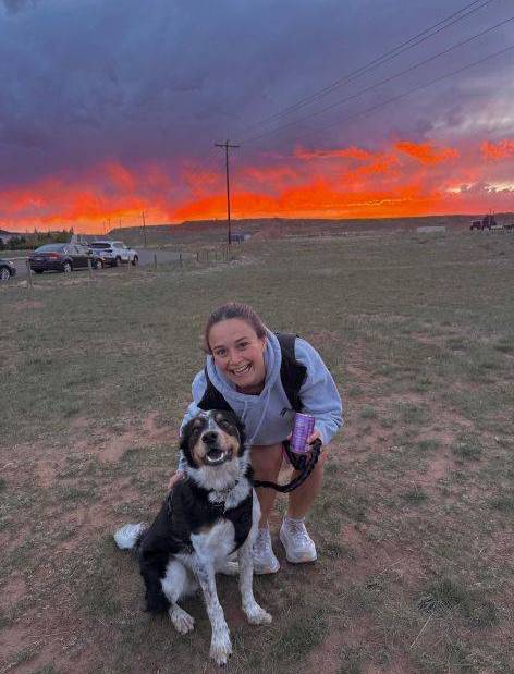 Brooklyn standing in a grassy plain with medium sized dog.