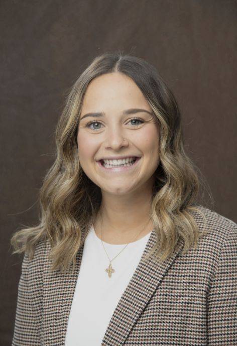 Brooklyn Prince wearing a tan plaid blaszer and a white blouse.