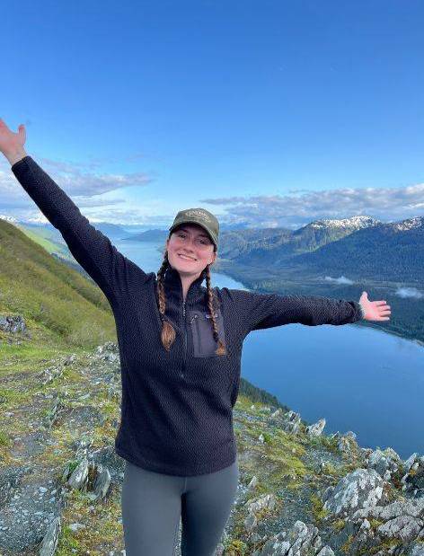 Zoe posing next to a large lake while hiking.