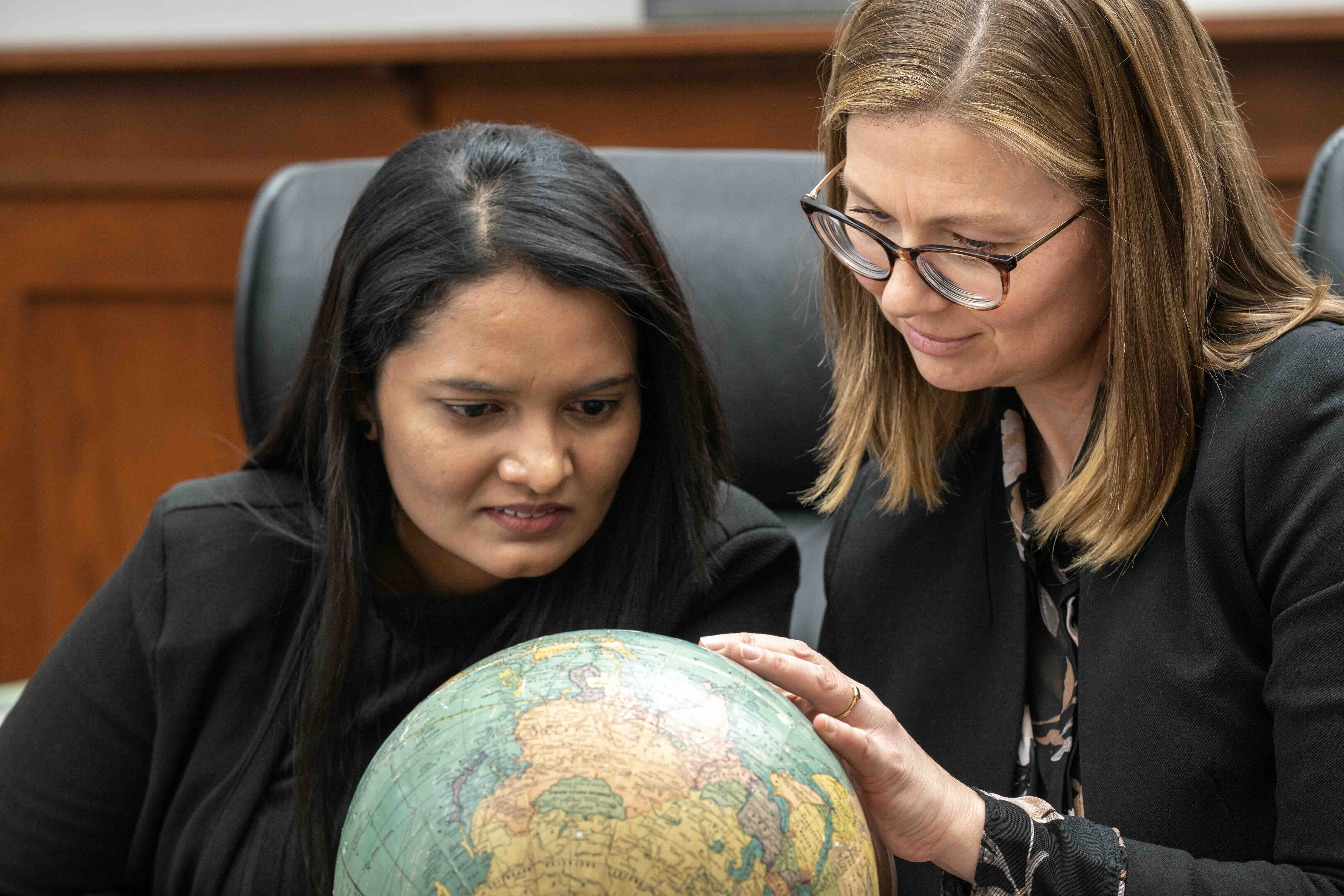 Photo of two people examining a globe.