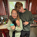 Xander Lindsey in a kitchen hugging family