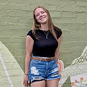 Cora Remacle posing in front of a mural