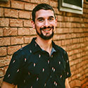 Daniel Burns smiling in front of a brick wall