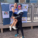 Photo of Priscilla Phan holding her daughter in front of a homemade quilt