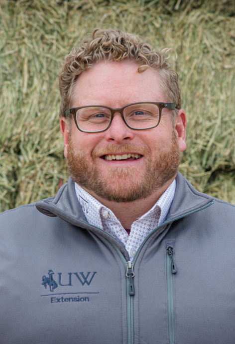 Dr. Whit Stewart Associate Professor Extension Sheep Specialist, standing in front of hay bales
