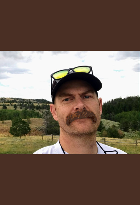 Matthew Carling stands in front of rolling hills and trees.