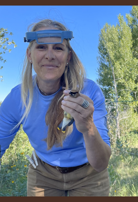 Anna Chalfoun holds a bird while wearing magnifying glasses