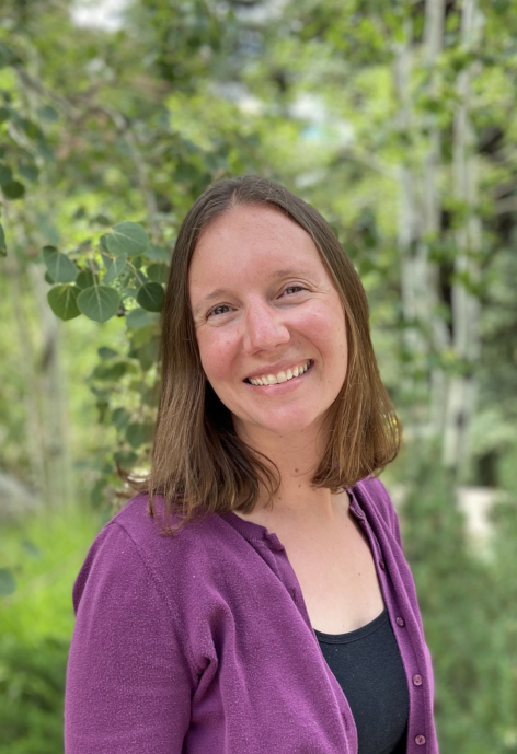 Sarah Collins smiles while standing in front of aspen trees.
