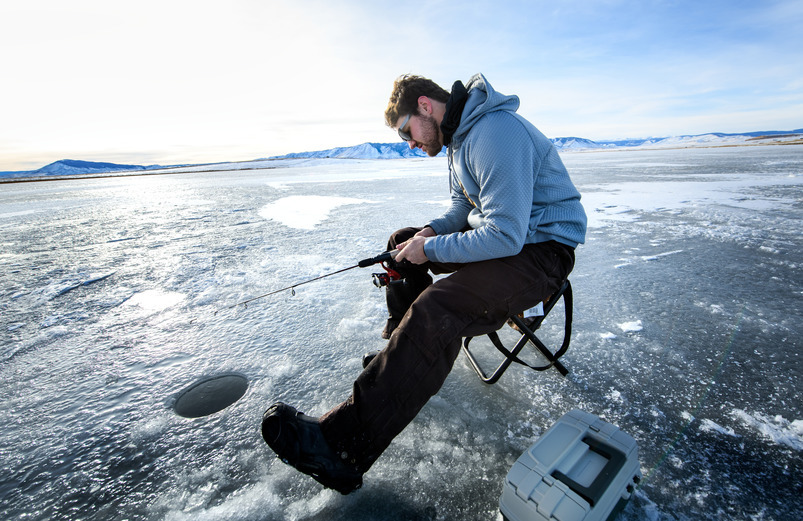 A graduate student ice fishes as part of a research project.